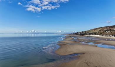 A sunny day, during low tide, the beach is vast and sandy