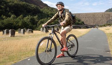 Man cycling in front of a dam at Elan Vlaley