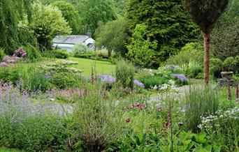 The blue garden filled with spring flowers with lawn in the background