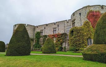 The East Front of Chirk Castle from the gardens, showing autumn colour in the leaves of the climbing plants on the castle walls and yew topiary in the