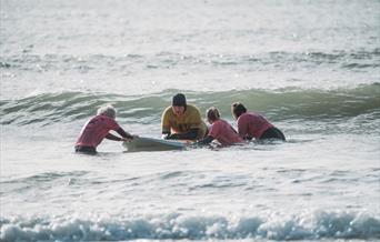 Volunteers helping Lion Gavin to surf at Caswell Bay, Swansea