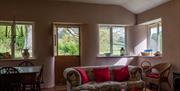 Sitting room with woodburner and fireguard,  comfy sofas, dining table, books and games. French doors to veranda with far reaching views