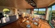 Eco Barn Upstairs Interior: dining table, sofas, desk, round window, sliding doors to balcony