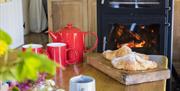 Flowers and croissants on a table in front of a lit log burner