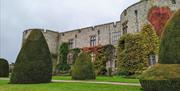 The East Front of Chirk Castle from the gardens, showing autumn colour in the leaves of the climbing plants on the castle walls and yew topiary in the