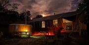 Safari tent at night with wood fired hot tub in the foreground