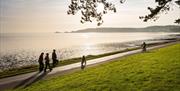 Cyclist and walkers on Coast Path at Blackpill at sunrise