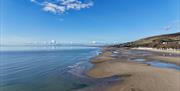 A sunny day, during low tide, the beach is vast and sandy