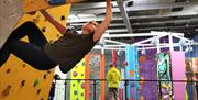 Woman climbs unroped over crash mats, while man watches CrazyClimb