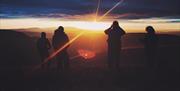 Four people watching the sunset over layers of mountains of the Brecon Beacons
