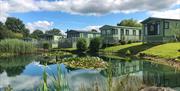 This photo shows a row of caravans overlooking a mature fishing and nature pools. In the warmer months you are treated to an array of colours in the p