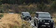 Land Rovers in convoy on rocky terrain.