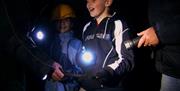 Girl and Boy exploring with torches at Corris Mine Explorers
