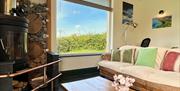 Loom Cottage woodburner, large picture window and sofa.