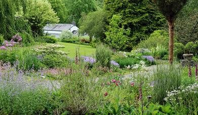 The blue garden filled with spring flowers with lawn in the background