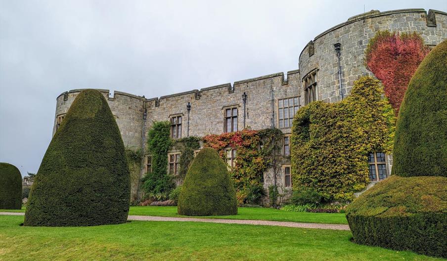 The East Front of Chirk Castle from the gardens, showing autumn colour in the leaves of the climbing plants on the castle walls and yew topiary in the