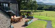 The Longhouse at Hilltops Brecon Holiday Cottages has a private outdoor patio area with views across open fields to the Camarthen Fans