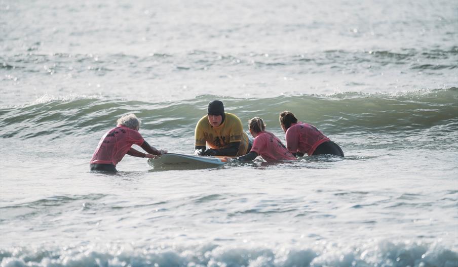 Volunteers helping Lion Gavin to surf at Caswell Bay, Swansea
