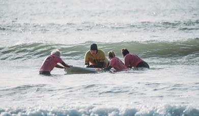 Volunteers helping Lion Gavin to surf at Caswell Bay, Swansea